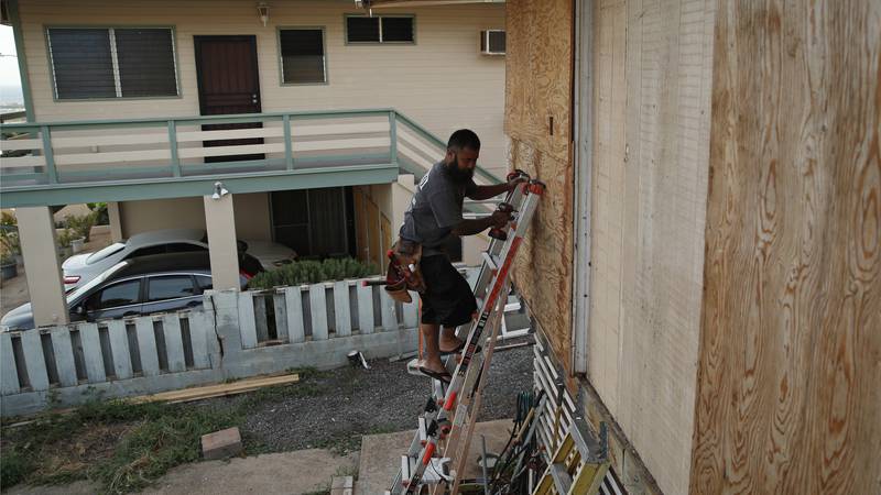 Kaipo Popa secures plywood to protect windows on a home in preparation for Hurricane Lane,...