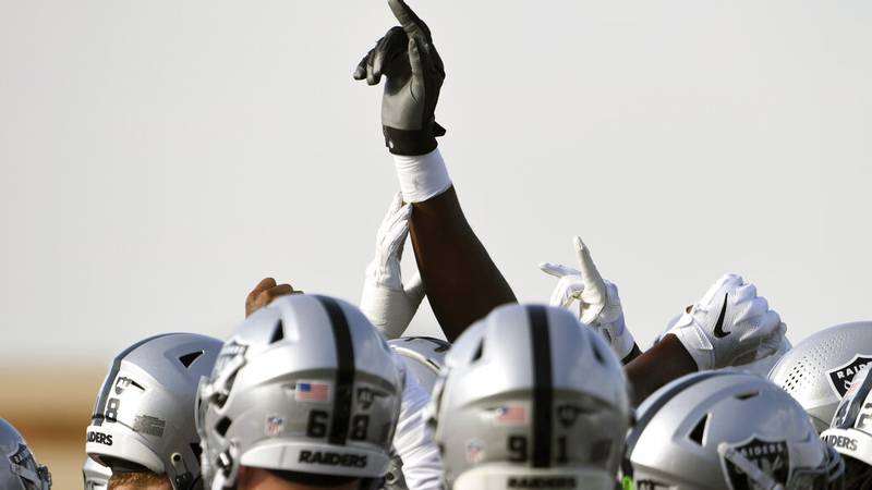 A hand is raised as the Las Vegas Raiders huddle during an NFL football practice Thursday, July...