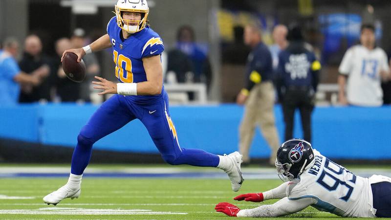 Los Angeles Chargers quarterback Justin Herbert (10) scrambles away from Tennessee Titans...